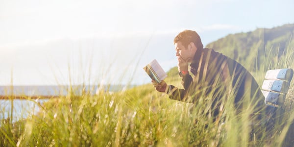 best year ever - man reading in field near ocean